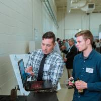 A student explaining something on a laptop to guests at the Engineering Design Project Preview